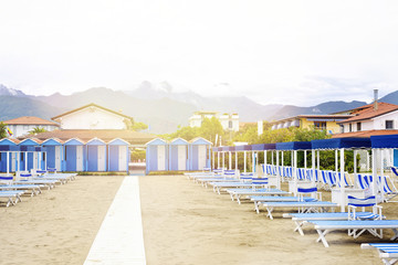 Daylight view to vibrant blue sunchairs and sunshades on beach.
