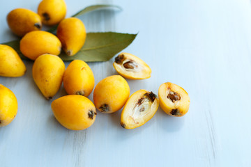 Loquat orange fruits on branch with leaves on a blue wooden background