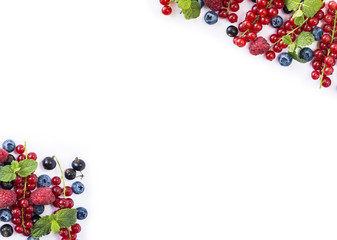 Mix berries and fruits at border of image with copy space for text. Ripe currants, blueberries and raspberries on white background. Top view.
