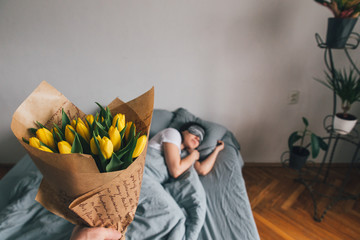 first person view. man bring flowers to bed for sleeping girlfriend. romantic surprise concept
