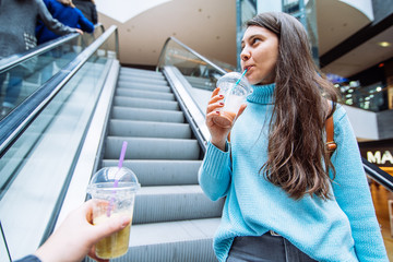 woman with man on stairs in mall drink smoothies. lifestyle concept. first-person view.