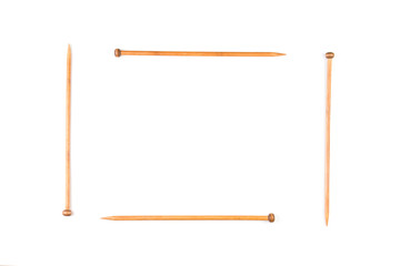 Wooden knitting needles arranged as frame on white background