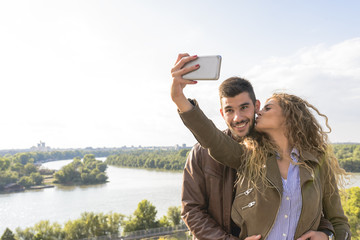 Happy young couple taking selfie photos near the river