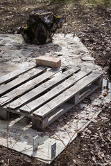 construction object started; wooden pallet and brick in a building site; old strain and wooden...