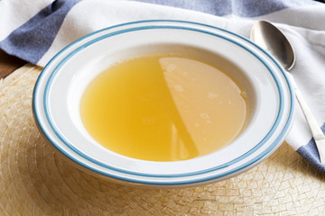 Chicken bone broth served in a white and blue plate