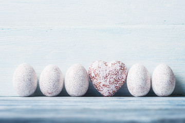 White painted Easter eggs and heart on wooden background.