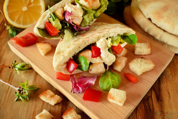 Caesar salad in pita bread on a wooden board