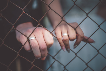 Married couple showing a wedding rings through iron fence.