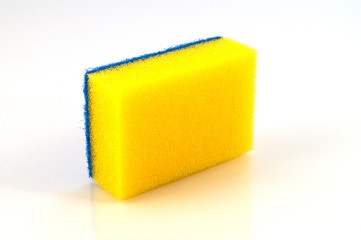Губка для чистки поверхностей яркого желтого цвета, уложенная на ребро.