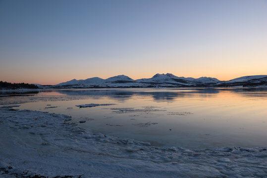 A Norwegian fjord near Tromsø covered with ice at sunset, Tromsø, Norway