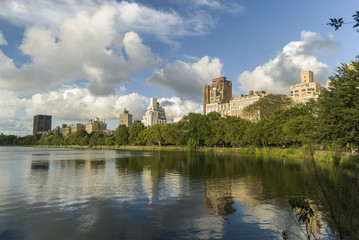 Fototapeta na wymiar Central Park reflection/Residencial building overlooking the Central Park and reflecting into the lake on a summer cloudy afternoon.