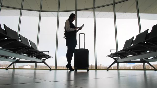 businesswoman at the airport. silhouette of a girl with mobile phone and luggage baggage suitcase, tablet. business and travel woman in terminal office railway bus station