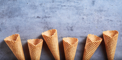 Border of empty ice cream sugar cones on slate