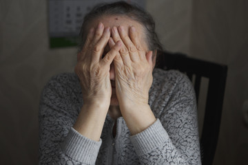 An elderly woman sitting at the table in a depressed state,