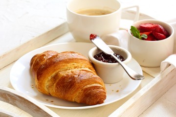 Breakfast in Bed with Croissant Jam strawberries and Coffee in tray, selective focus