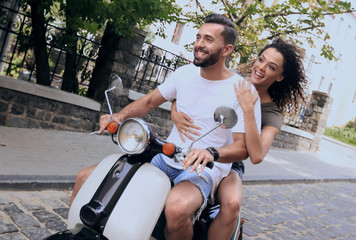 Obraz premium Stylish young couple sits a scooter in the street.