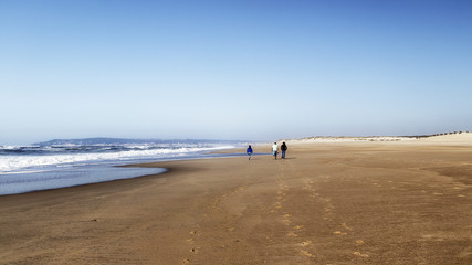 Fototapeta na wymiar Tres personas caminando por la playa