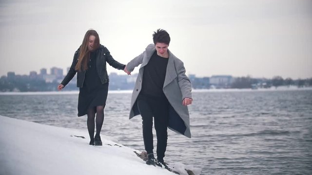 Happy young couple running on the snowy riverside