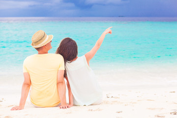 back view of couple sitting on a tropical beach on Maldives