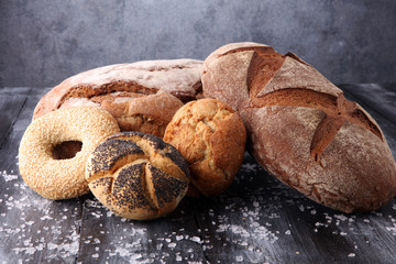 Different kinds of bread and bread rolls on board from above. Kitchen or bakery poster design.
