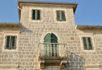 Fototapeta na wymiar Villa built of stones with two floors and a balcony with iron fence