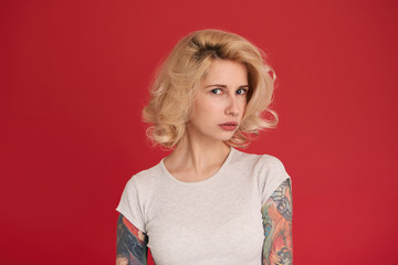 Attractive blonde female, wears casual t-shirt feels abused, sad and unhappy, looks into camera...