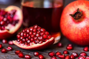 Ripe pomegranates with glass of juice on table