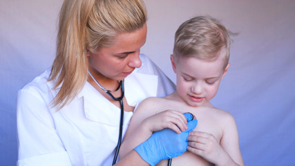 Young beautiful woman, nurse, doctor, auscultation, little boy, patient, blue rubber gloves, stethoscope, white blue background.