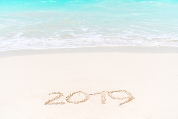 2019 handwritten on sandy beach with soft ocean wave on background