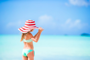 Adorable little girl in big red hat on the beach
