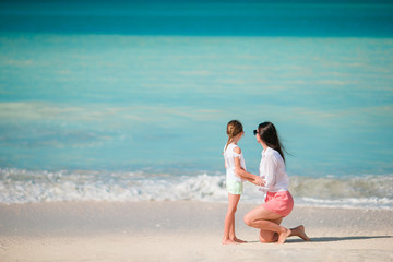 Beautiful mother and daughter on white beach