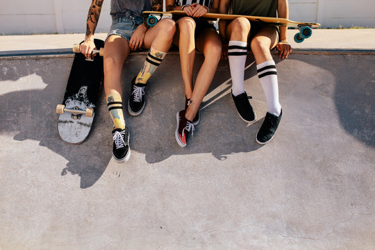 Legs of women sitting on ramp at skate park