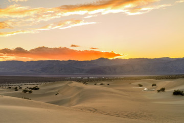 Fototapeta na wymiar Sunset Sand Dunes - A colorful Spring sunset at Mesquite Flat Sand Dunes, with Stovepipe Wells village seen at base of Panamint Range. Death Valley National Park, California, USA. 