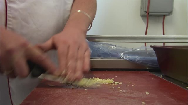 A medium shot of stove with a person chopping garlic
