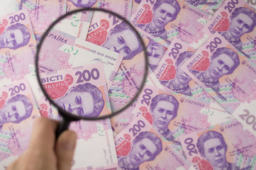Much money. Ukrainian hryvnia. Money under the magnifying glass