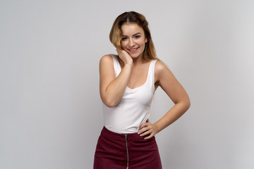 smiling cute girl in white blouse and skirt posing for horizontal Studio portrait on isolated grey background. 