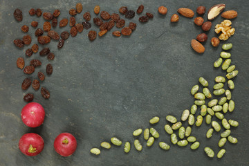 Vegan vegetables with radish, nuts and roasted soy beans on dark slate with copy space in center