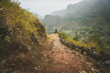 Fototapeta na wymiar Male hiker enjoying impressive mountainscape. Lash canyon valley extend far below. Santo Antao, Cabo Verde