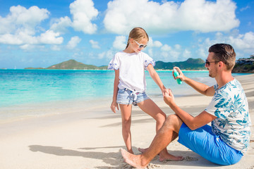 Young father applying sun cream to daughter on the beach. Sun protection