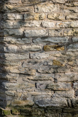 Old grey stone wall lighted by sunshine for texture or background shots.