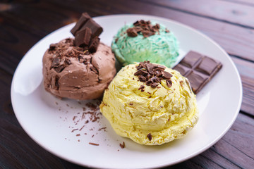 Mint, banana and chocolate ice cream scoops with chocolate crumbs served on white plate. Delicious refreshing summer sweets