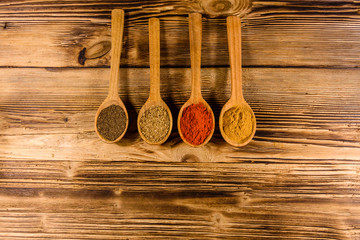 Spoons with the different spices on wooden table. Top view