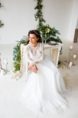 Beautiful model sitting in a white room decorated with green decor in a botanical style