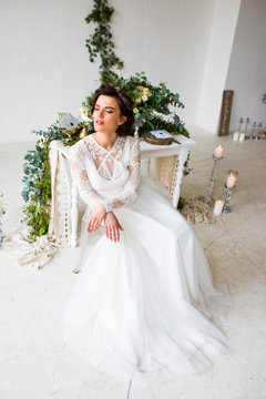 Beautiful model sitting in a white room decorated with green decor in a botanical style