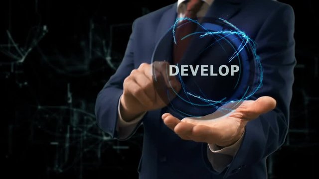 Businessman shows concept hologram Develop on his hand. Man in business suit with future technology screen and modern cosmic background