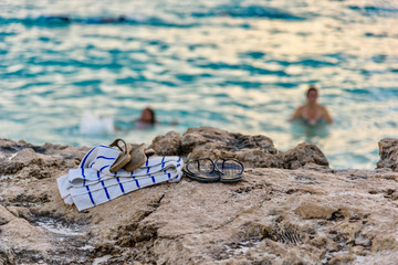 A towel and a pair of flip-flops on a cliff