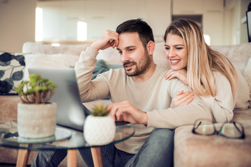 Beautiful young couple is using a laptop at home
