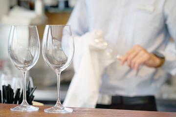 Obraz na płótnie Canvas The bartender wipes the wine glasses. The waiter wipes the wine glasses. Focus on the wine glasses. The concept of service.