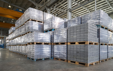 Paving slabs factory. Tiles piled in pallets. Warehouse paving slabs in the factory for its production