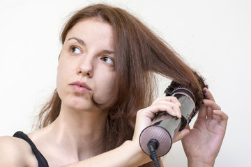 Fototapeta premium Redhead model using an air styler brush to dry and style her hair